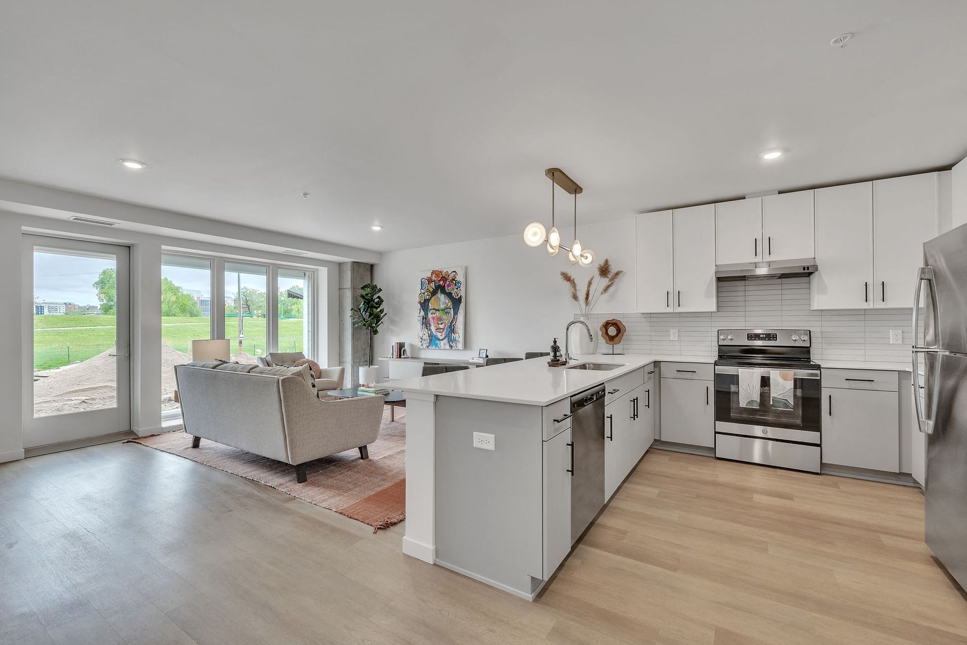 Open-concept kitchen and living area in a modern apartment with island and large windows at Esox House in St. Paul, MN.