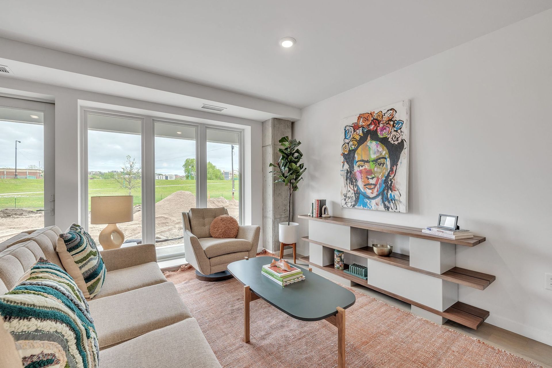 Bright living room with large floor-to-ceiling windows, beige sofa and chair, and wall art at Esox House in St. Paul, MN.