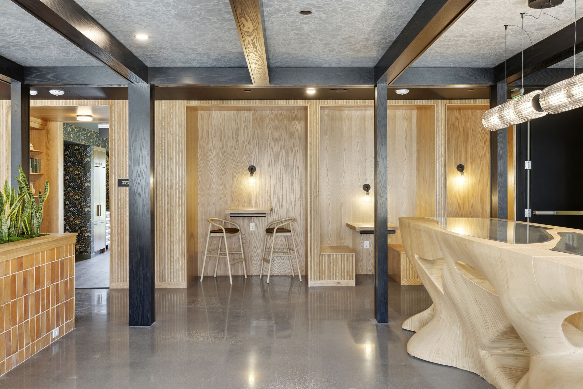 Bright clubhouse lounge with wood-paneled walls, bar-height seating, and modern lighting at Esox House in St. Paul, MN.