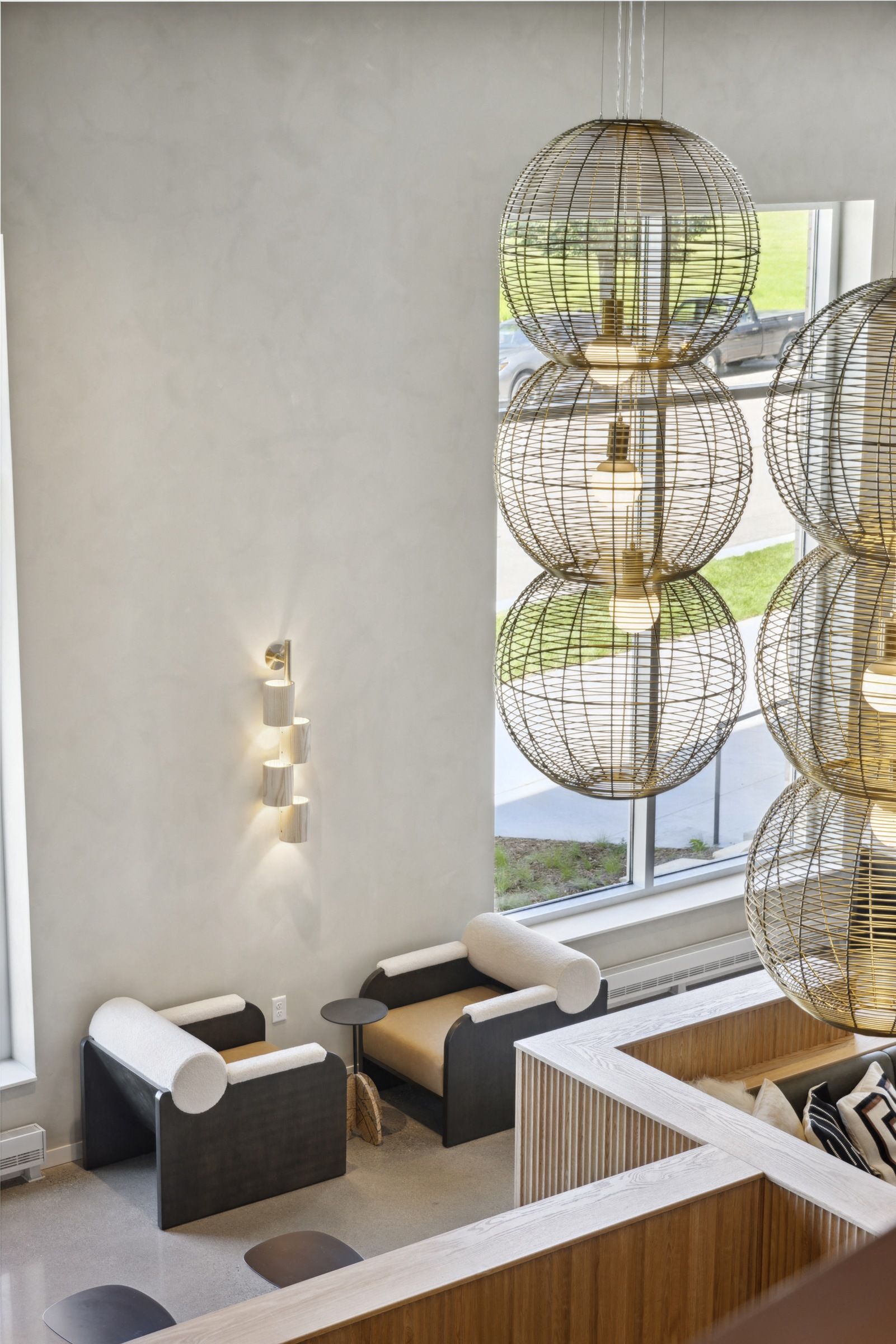 Interior lobby area with modular seating, warm lighting, and large wicker globe pendant lamps near windows at Esox House in St. Paul, MN.