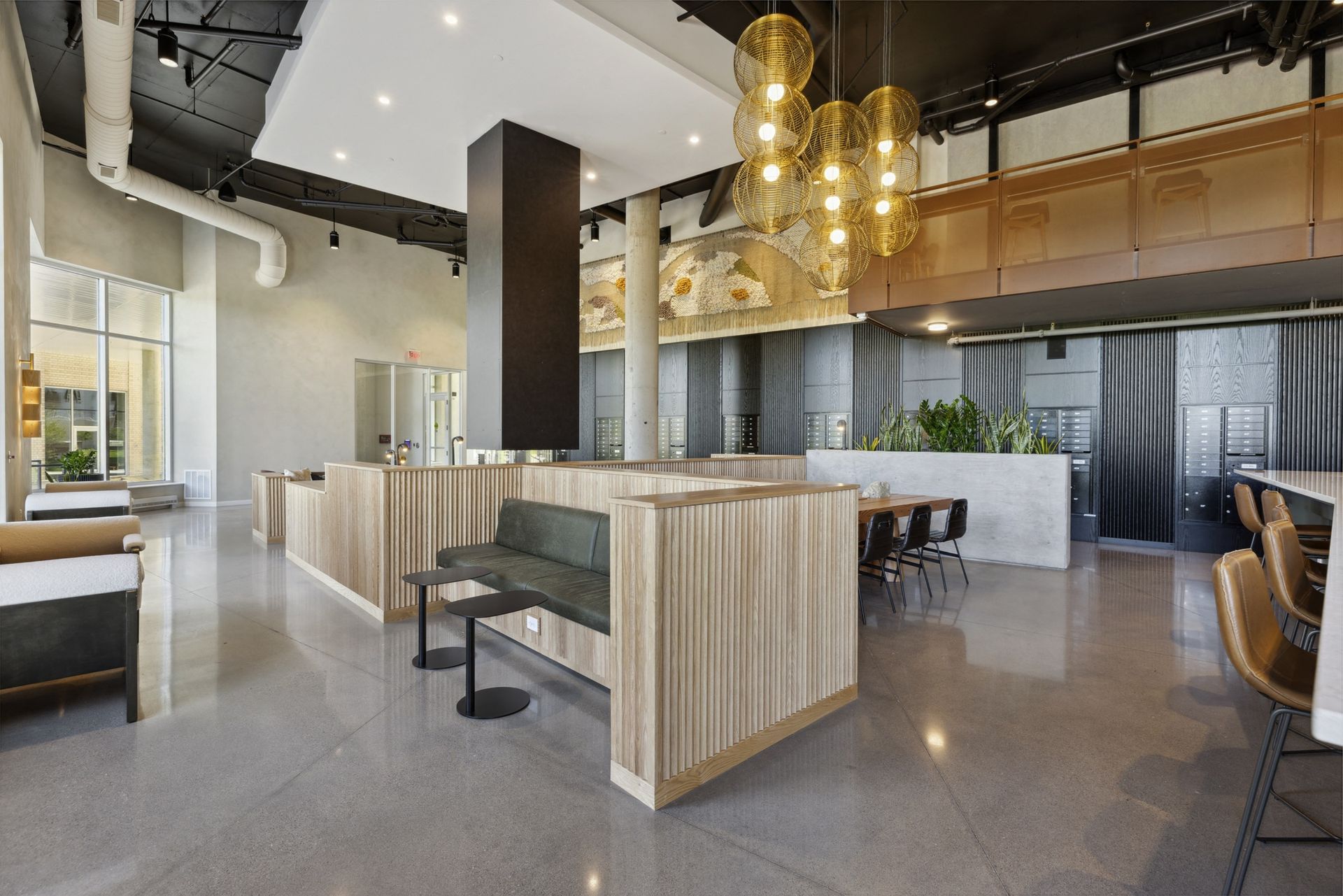 Open, modern residential lobby with wood-paneled partitions, lounge seating, and pendant lights at Esox House in St. Paul, MN.