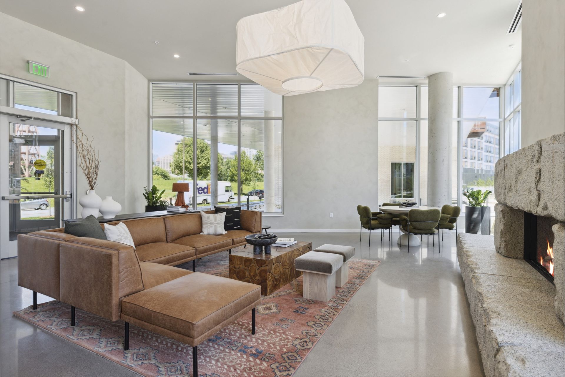Modern residential lobby with tan sectional sofa, large windows, and a stone fireplace at Esox House in St. Paul, MN.