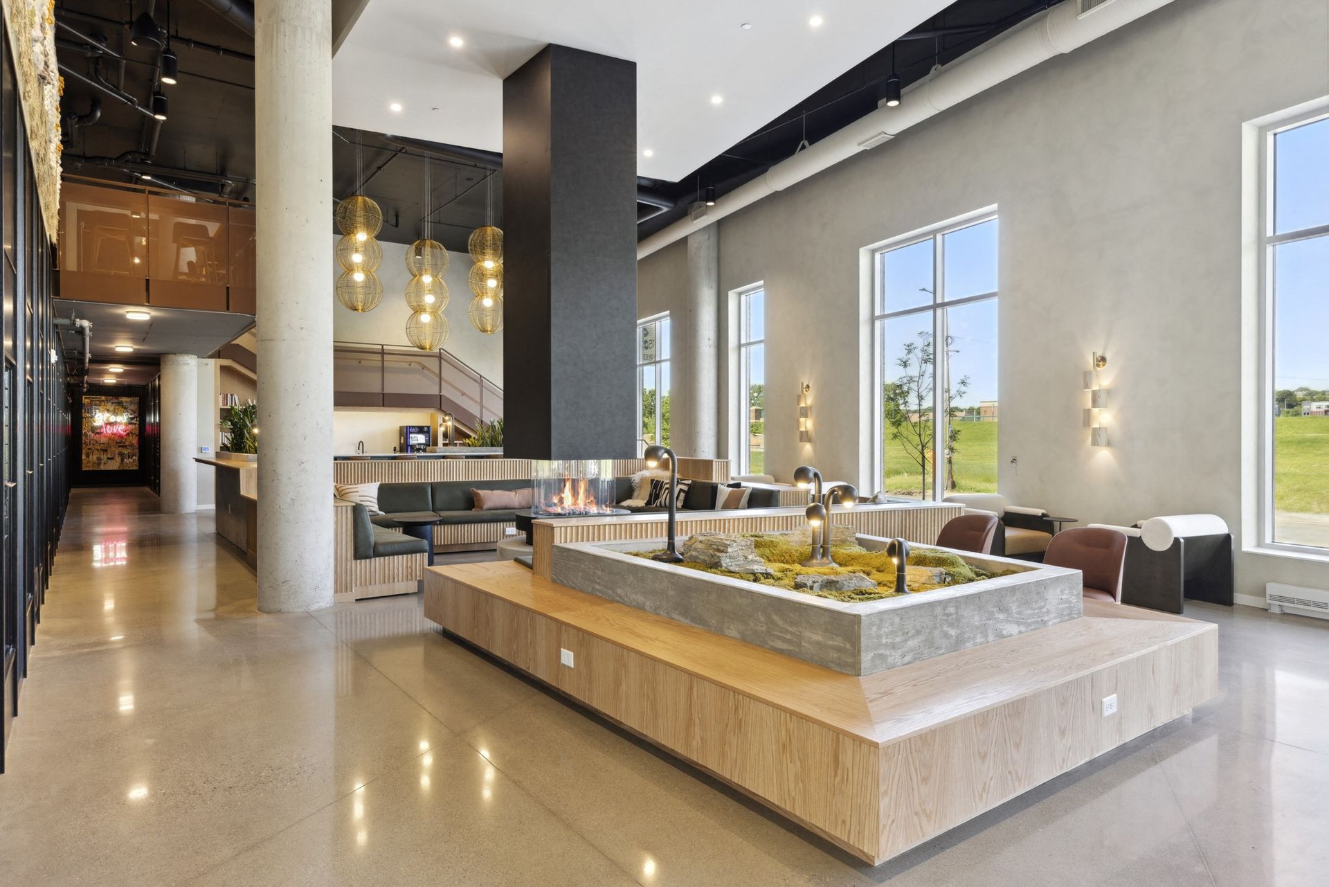 Modern apartment community lounge with ample seating, a central fireplace, and large windows at Esox House in St. Paul, MN.