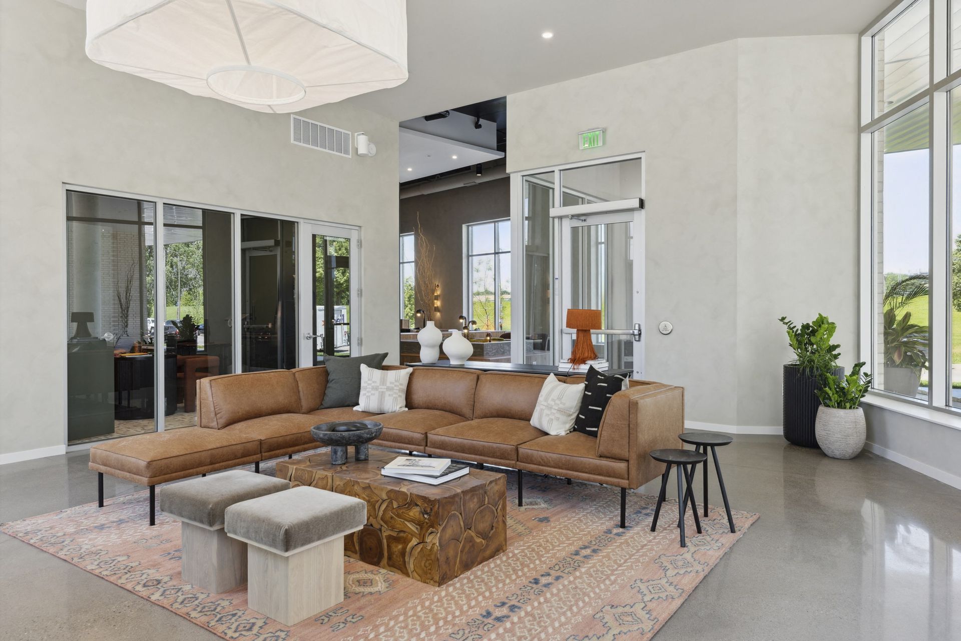 Modern resident lounge with a tan sectional sofa, coffee table, and large windows at Esox House in St. Paul, MN.