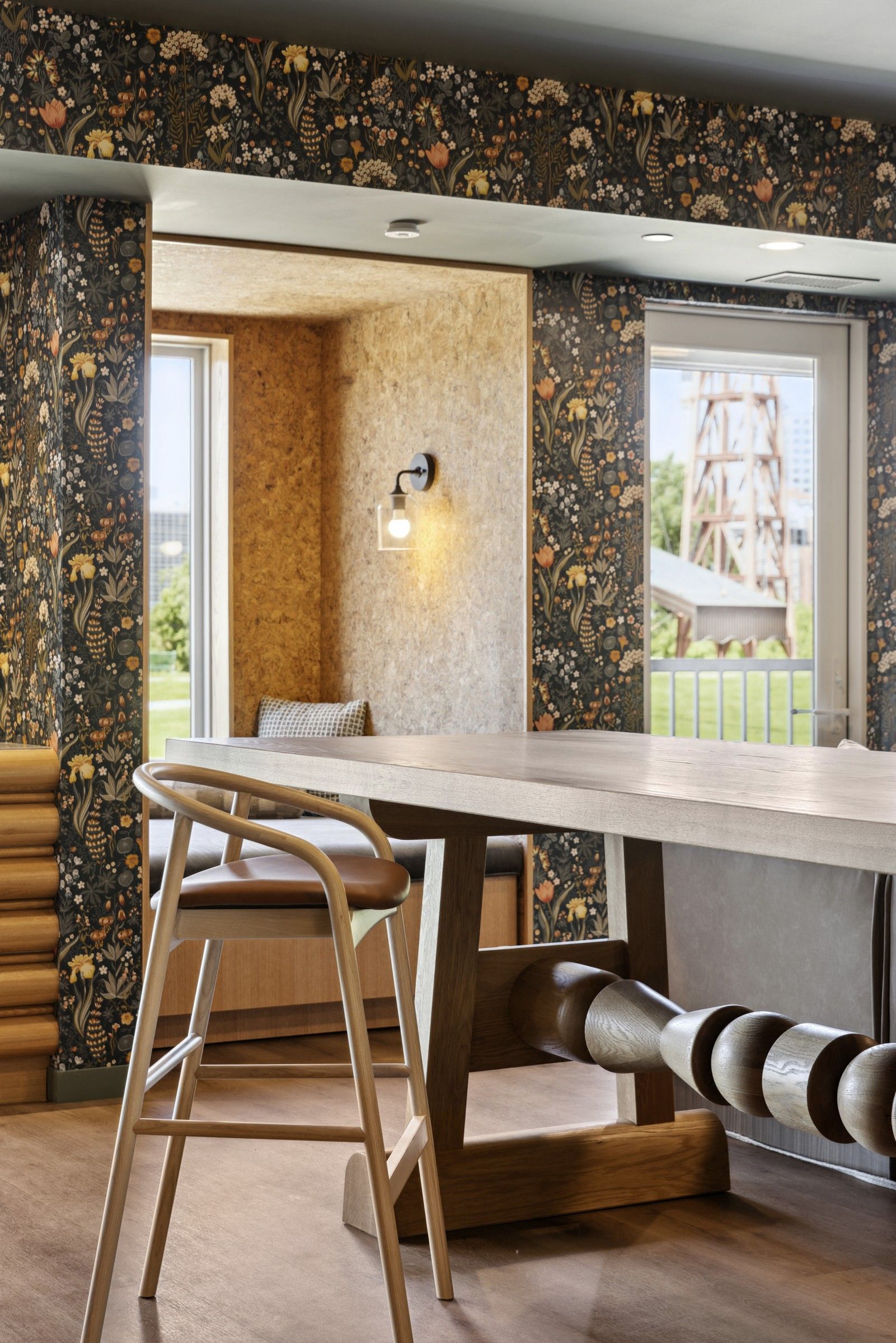Interior community lounge with a long wooden table and floral wallpaper at Esox House in St. Paul, MN.