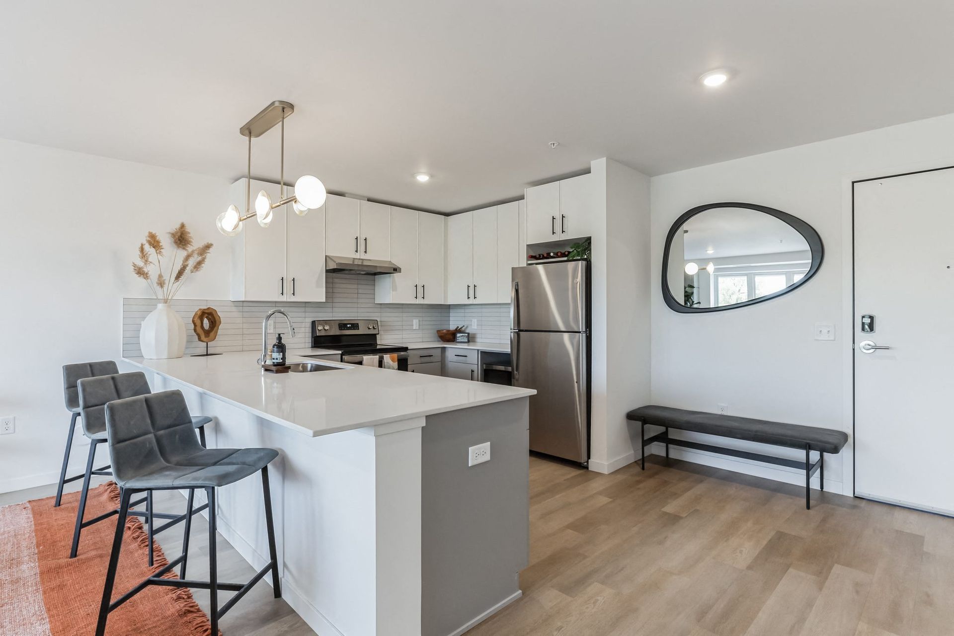 Bright kitchen with white cabinets, stainless steel appliances, and an island at Esox House in St. Paul, MN.
