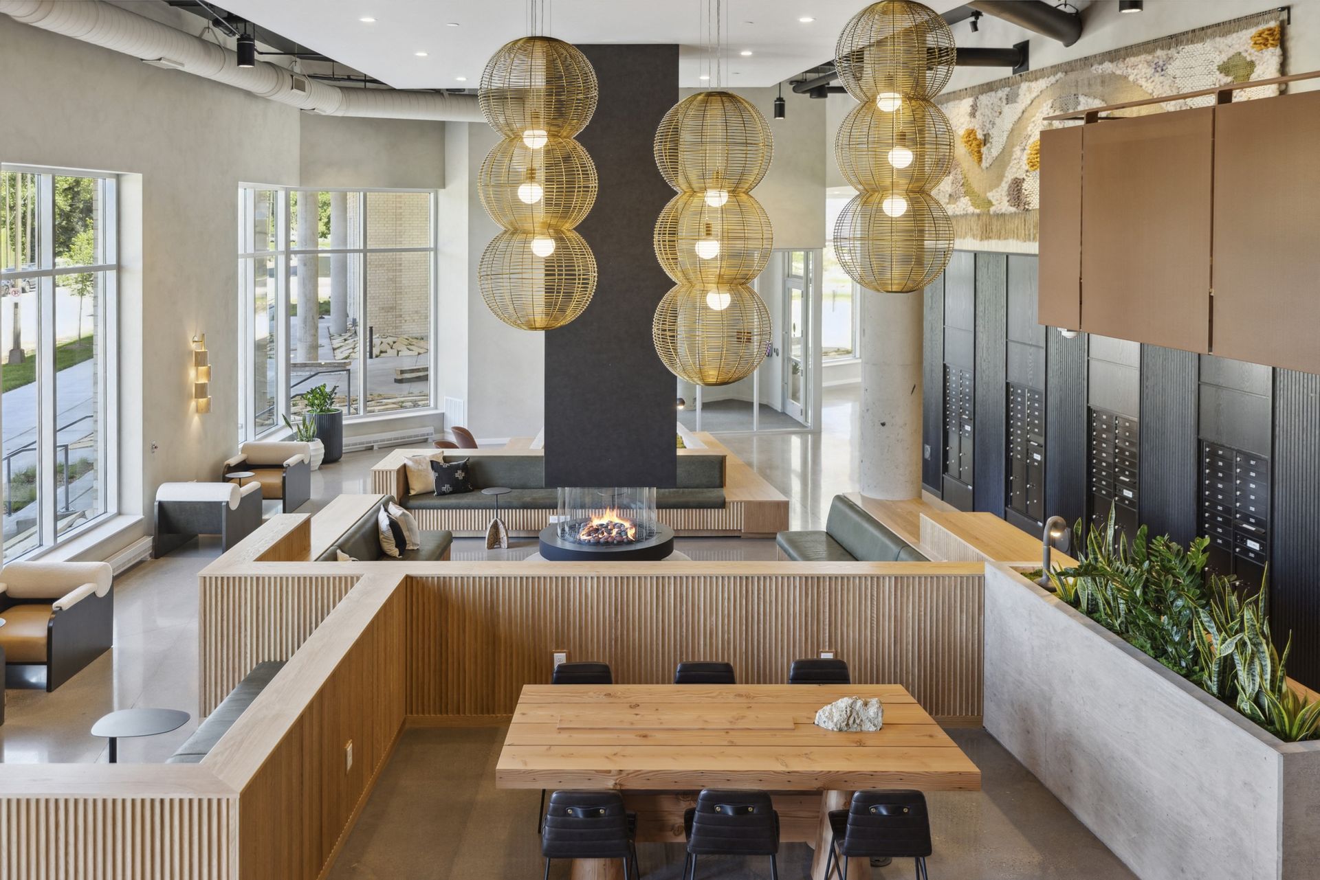 Open, well-lit communal lounge with large windows, seating areas, and a central fireplace at Esox House in St. Paul, MN.