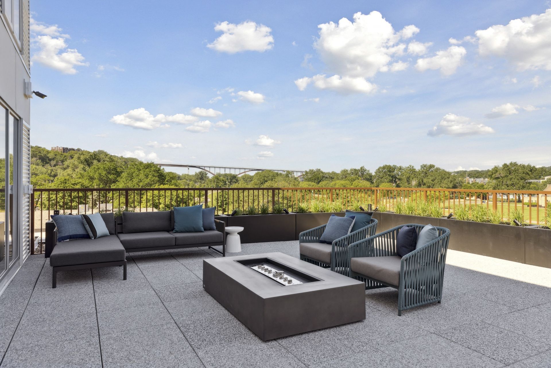Rooftop outdoor lounge on an apartment terrace with sectional sofas and a fire pit at Esox House in St. Paul, MN.