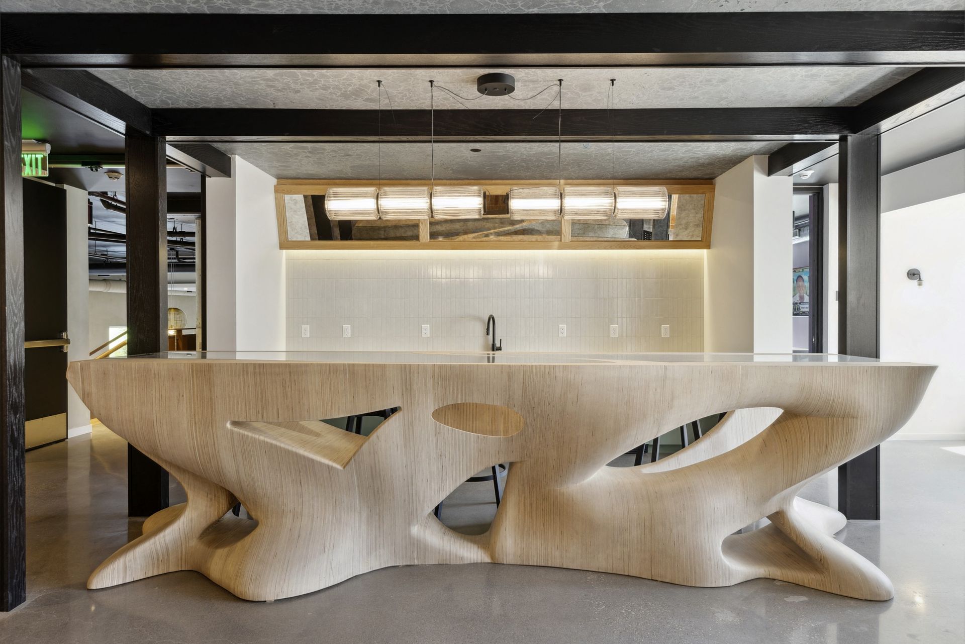 Contemporary communal kitchen/bar with a sculptural wood counter and pendant lighting at Esox House in St. Paul, MN.