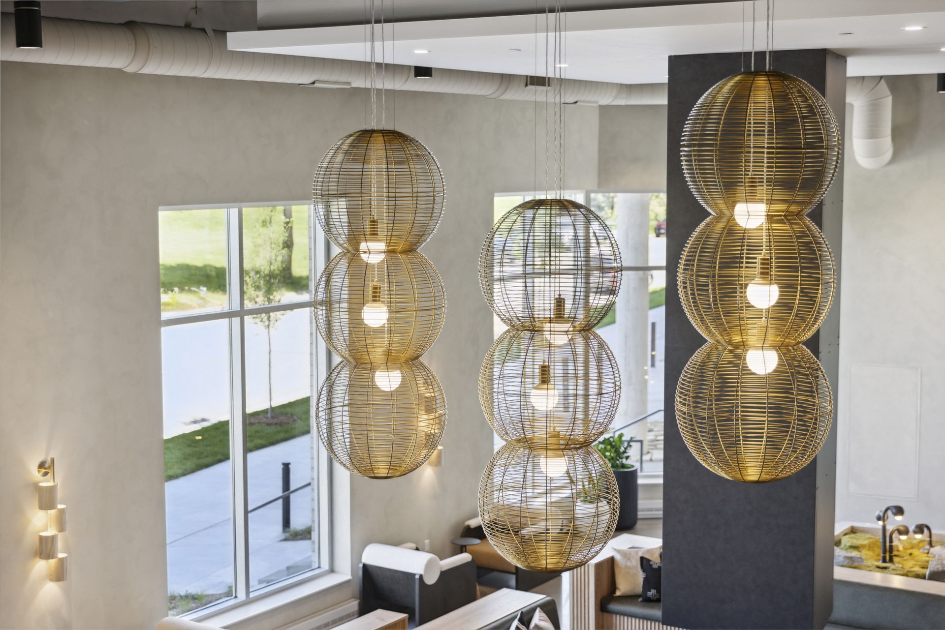 Interior lobby area with multiple large spherical woven pendant lights hanging over seating at Esox House in St. Paul, MN.
