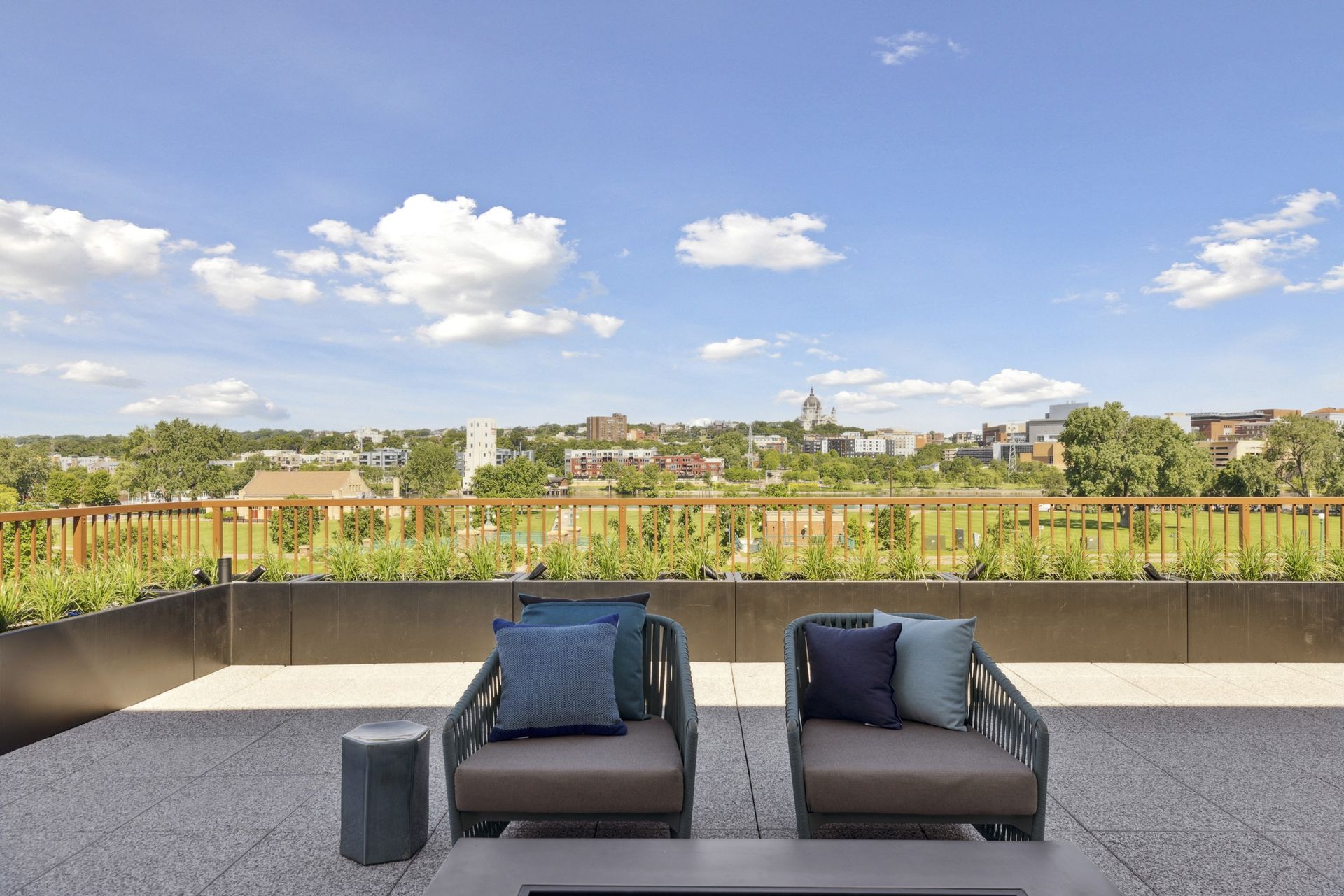 Rooftop terrace with cushioned seating and planters, city skyline in the distance at Esox House in St. Paul, MN.
