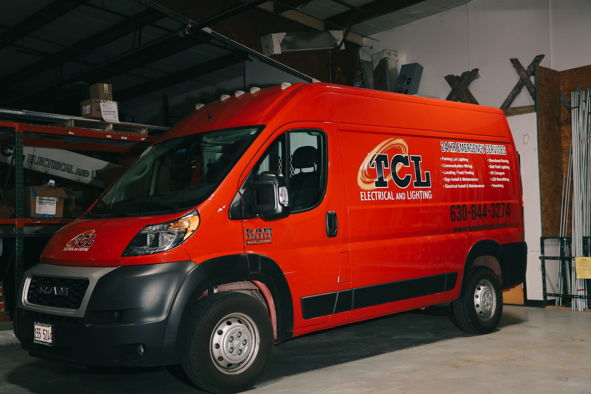 Two people in overalls reviewing papers and a laptop in a room with a ladder and large windows.