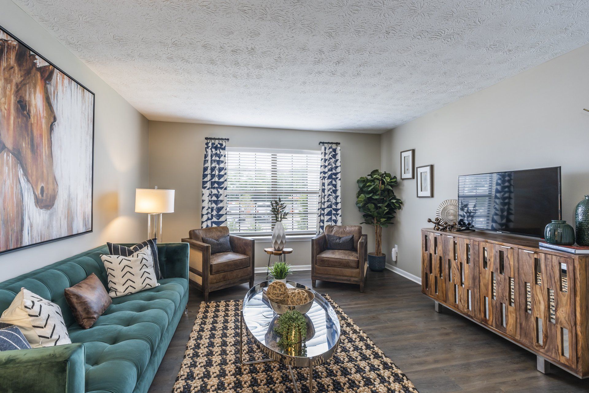 A living room with a couch, chairs, coffee table, and television at The Colony at the Oaks.