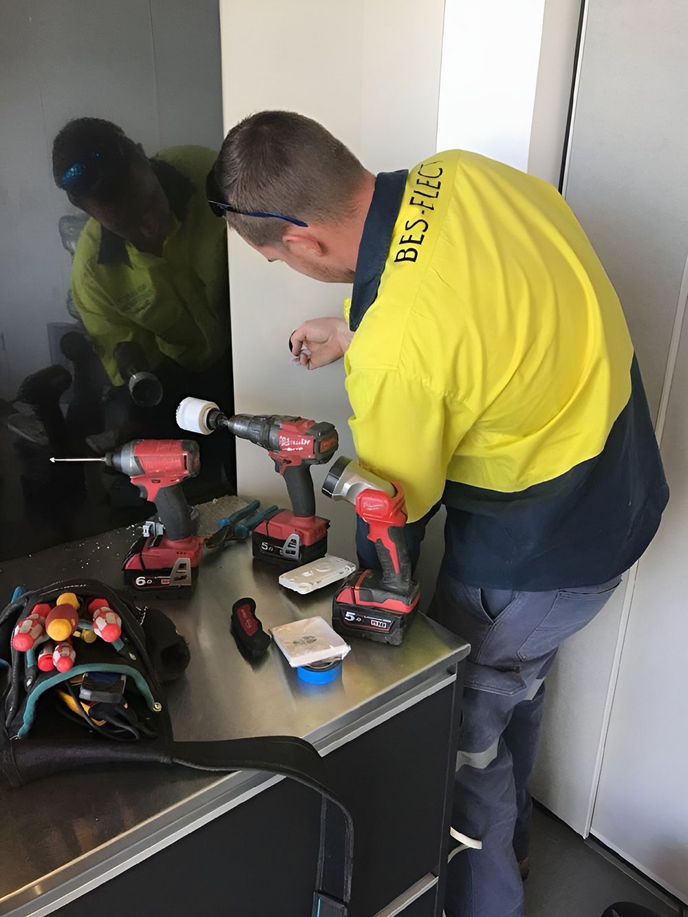 Electrician In Yellow Work Shirt Using Power Tools