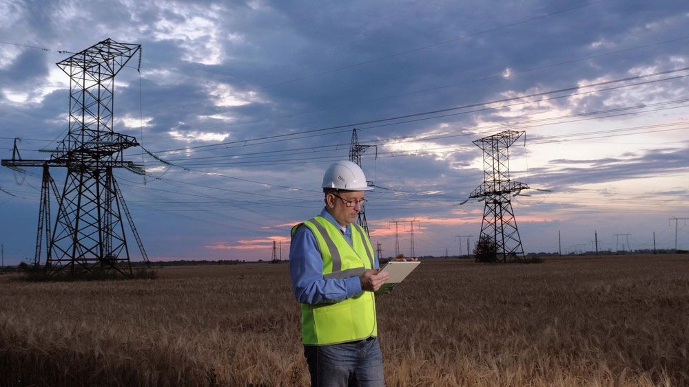 Electrician in a Field Looking at a Tablet - Rural Electrician in Tamworth, NSW