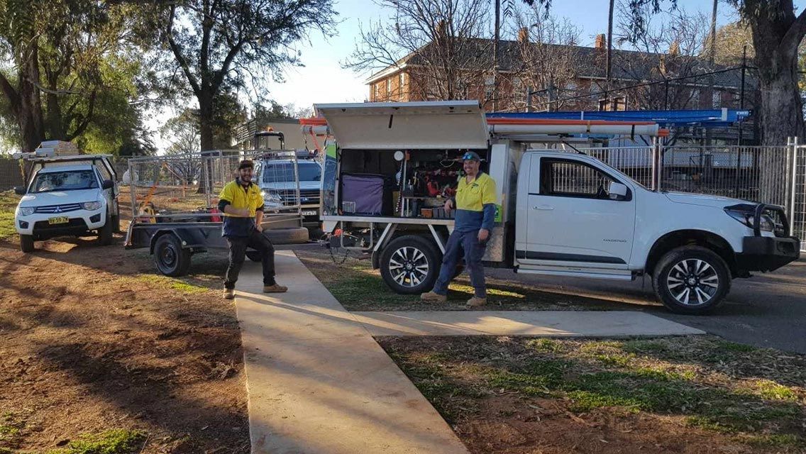 Two Electricians Standing Beside A Vehicle