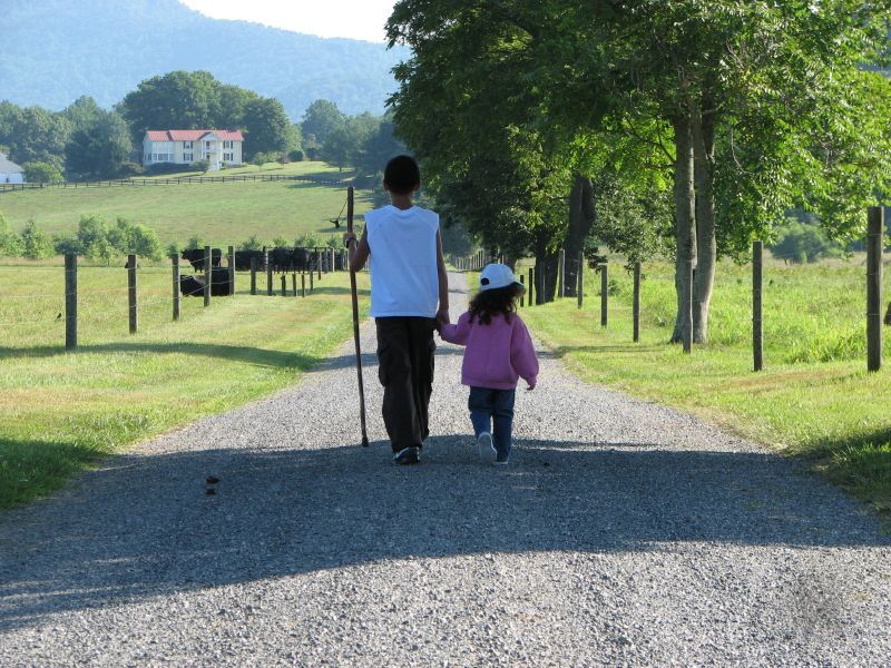 A boy and a girl are walking down a gravel road holding hands
