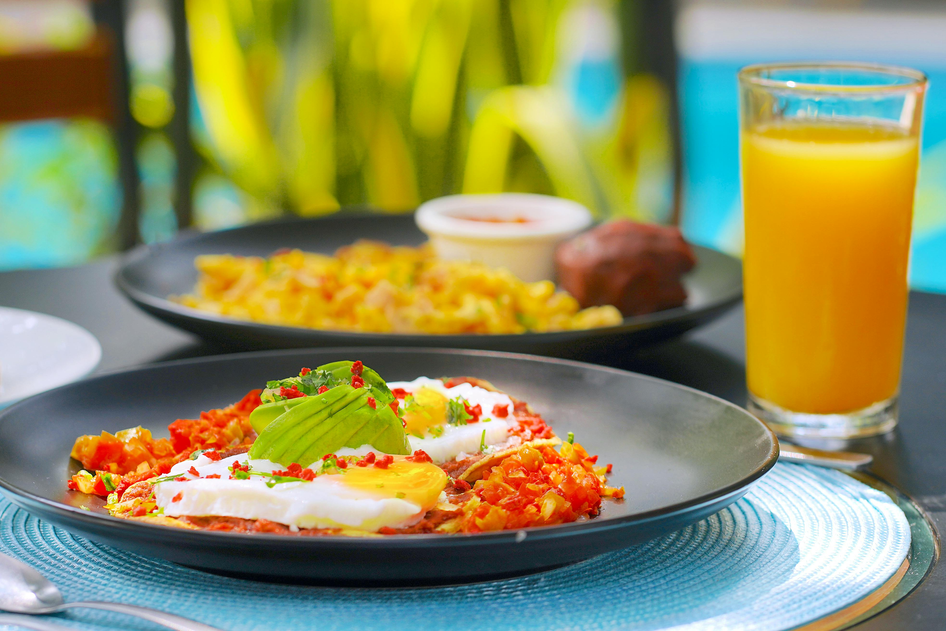 A plate of food and a glass of orange juice on a table.