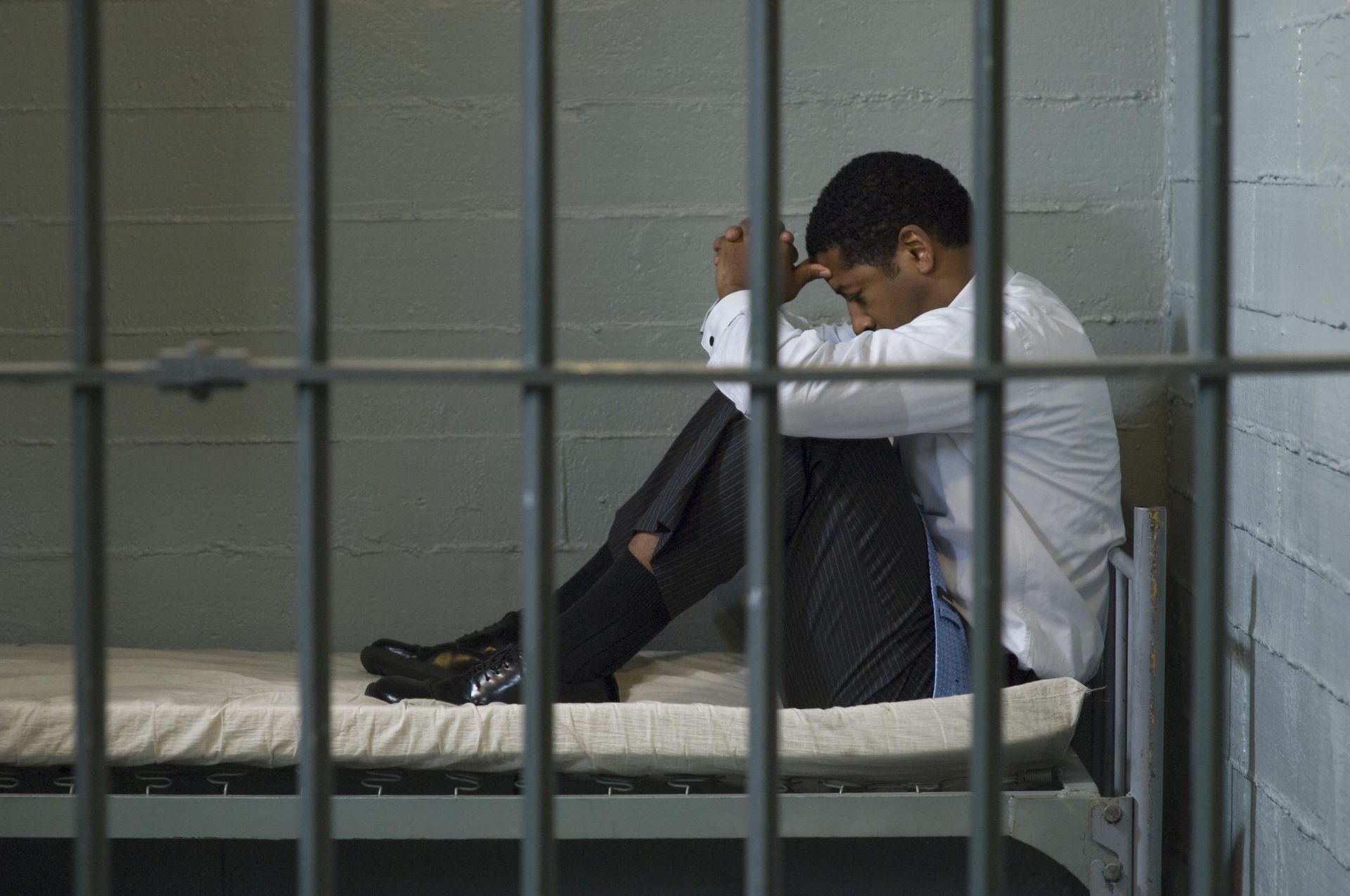 A man in a white sleeve inside the jail.