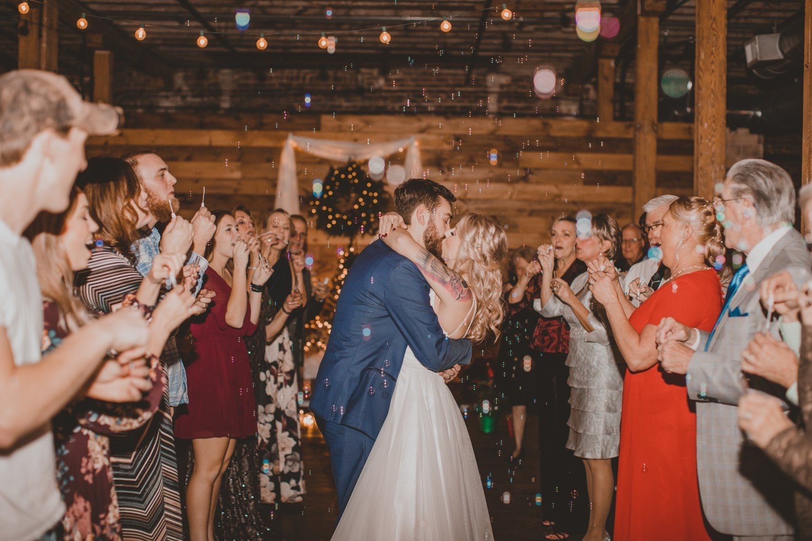 A bride and groom are kissing in front of their wedding guests.