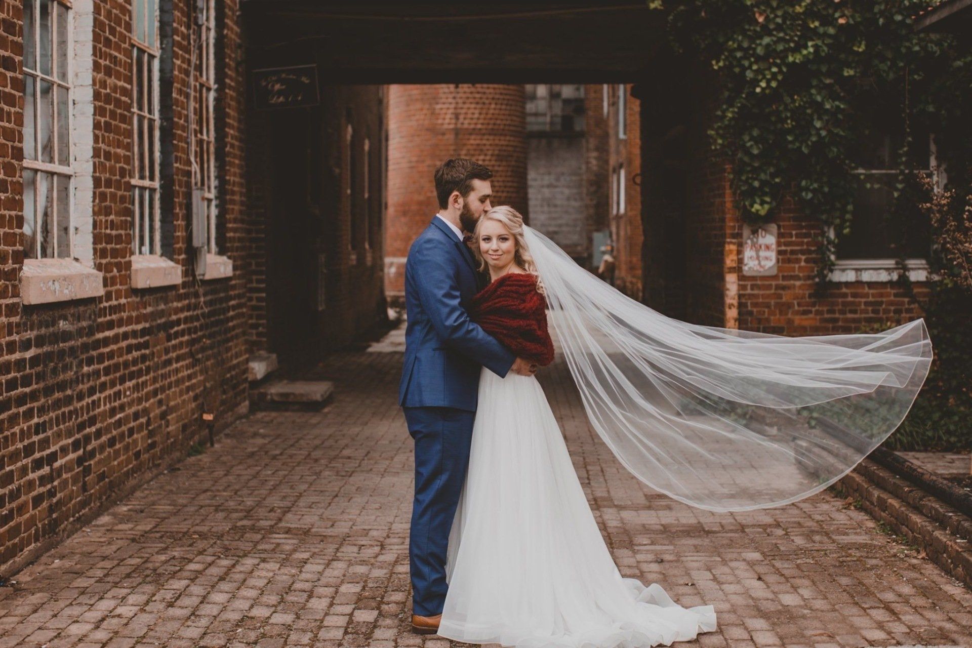 A bride and groom are posing for a picture on a cobblestone street.