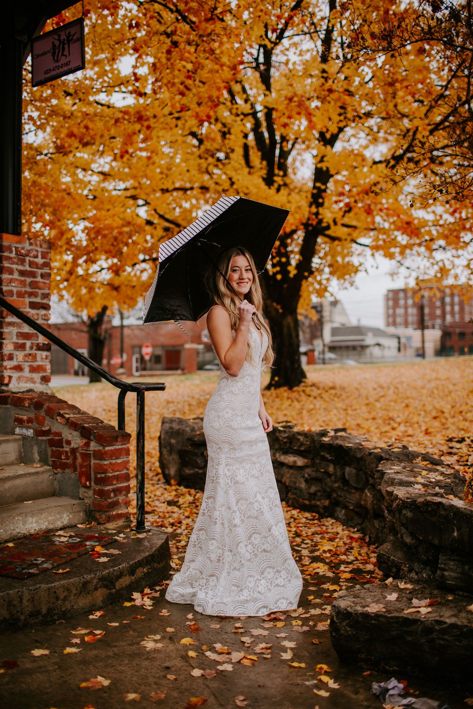 A woman in a wedding dress is holding an umbrella in the rain.