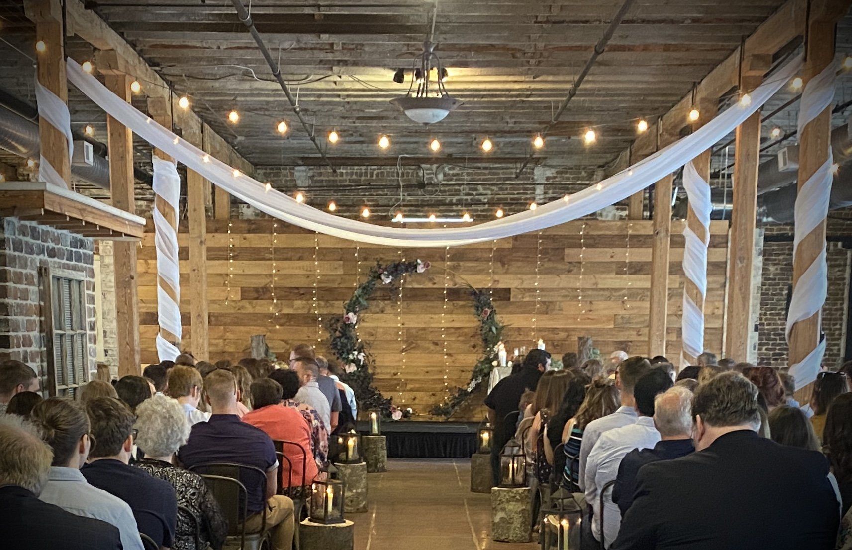 A large group of people are sitting in a room watching a wedding ceremony.
