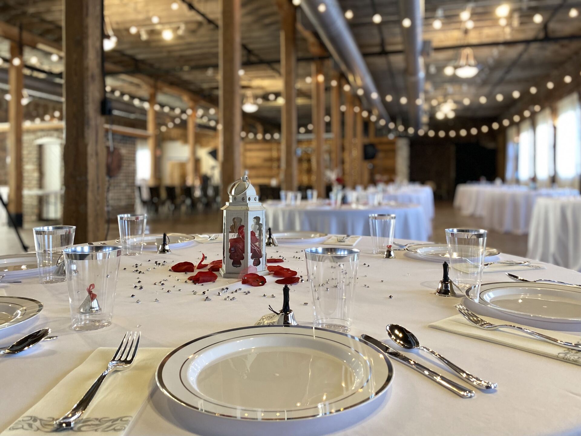 A table set for a wedding reception with plates , silverware , glasses and candles.