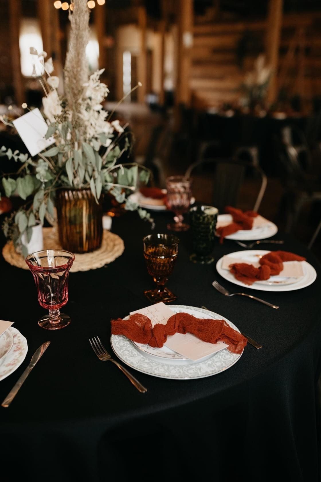 A table set for a wedding reception with plates , glasses , and napkins.