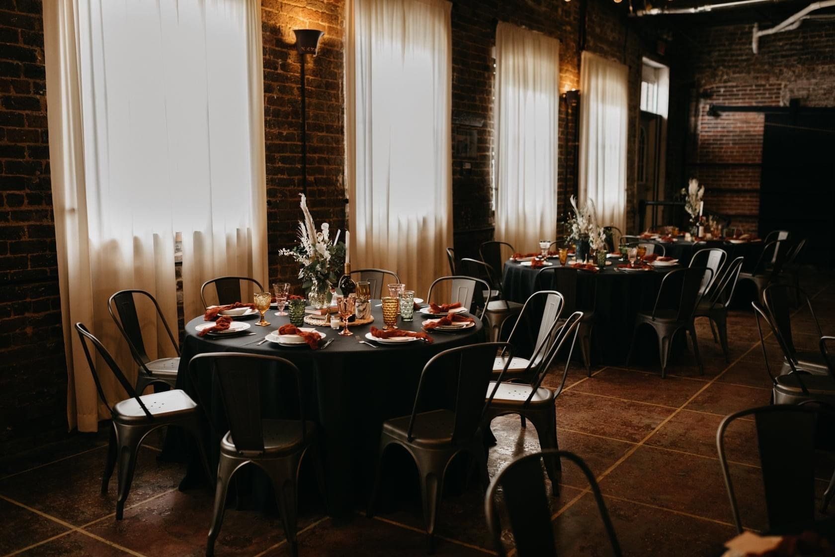 A room with tables and chairs set up for a wedding reception.