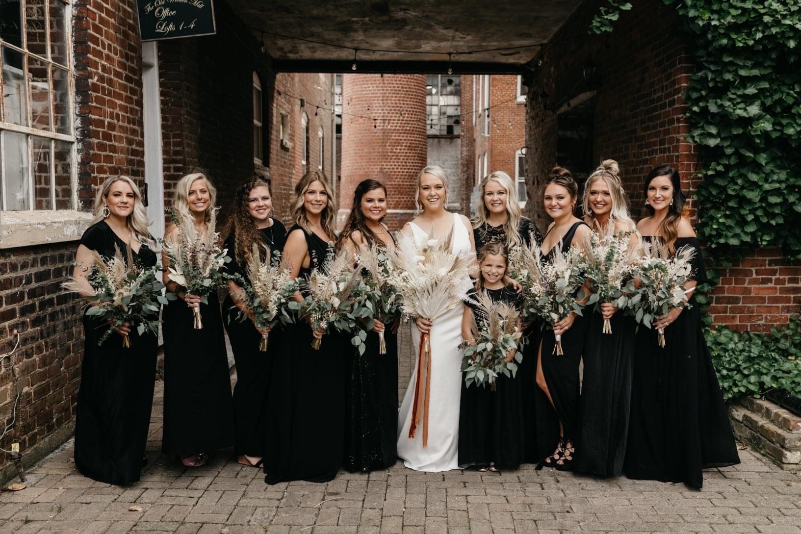 A bride and her bridesmaids are posing for a picture in front of a brick building.