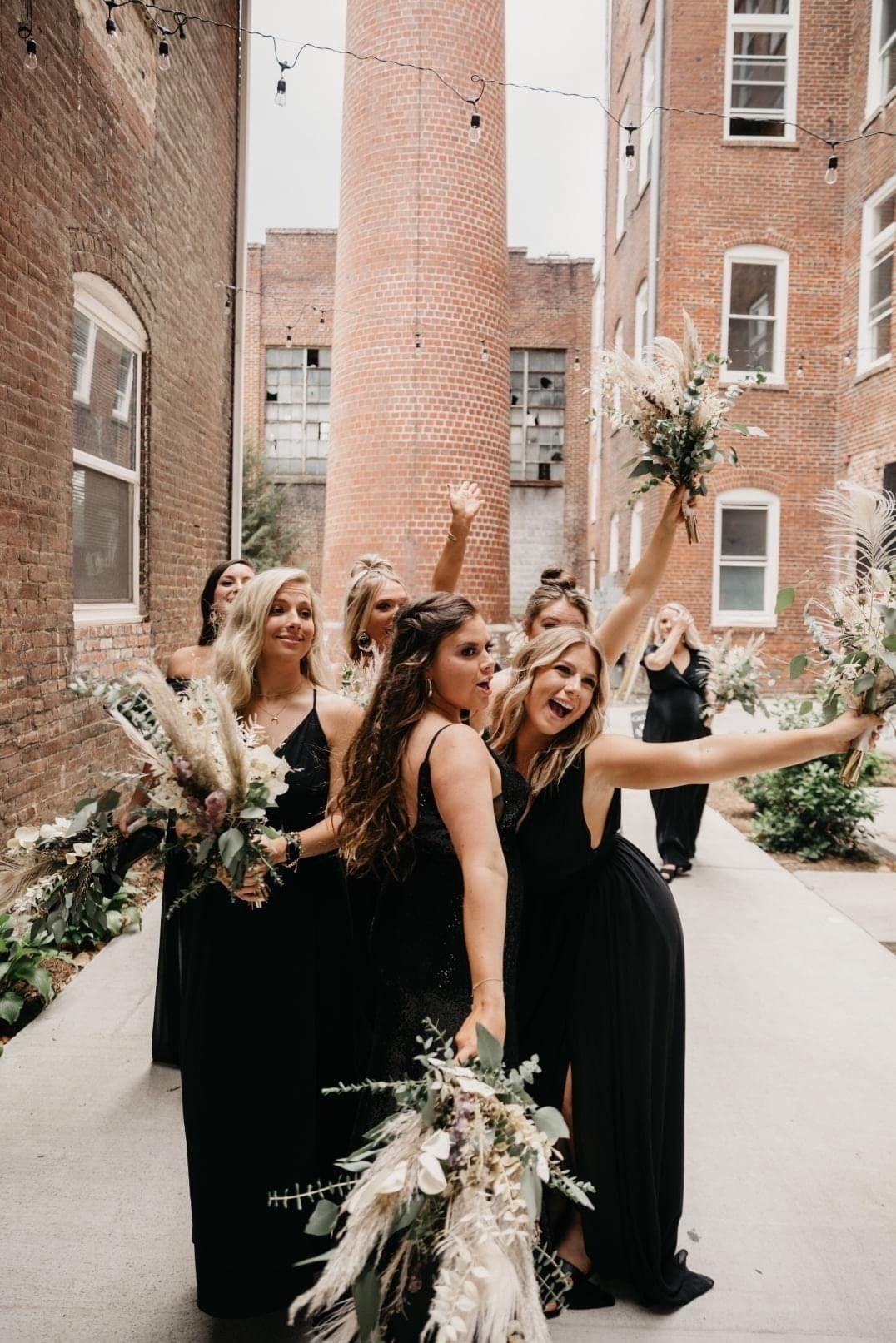 A bride and her bridesmaids are posing for a picture in front of a brick building.