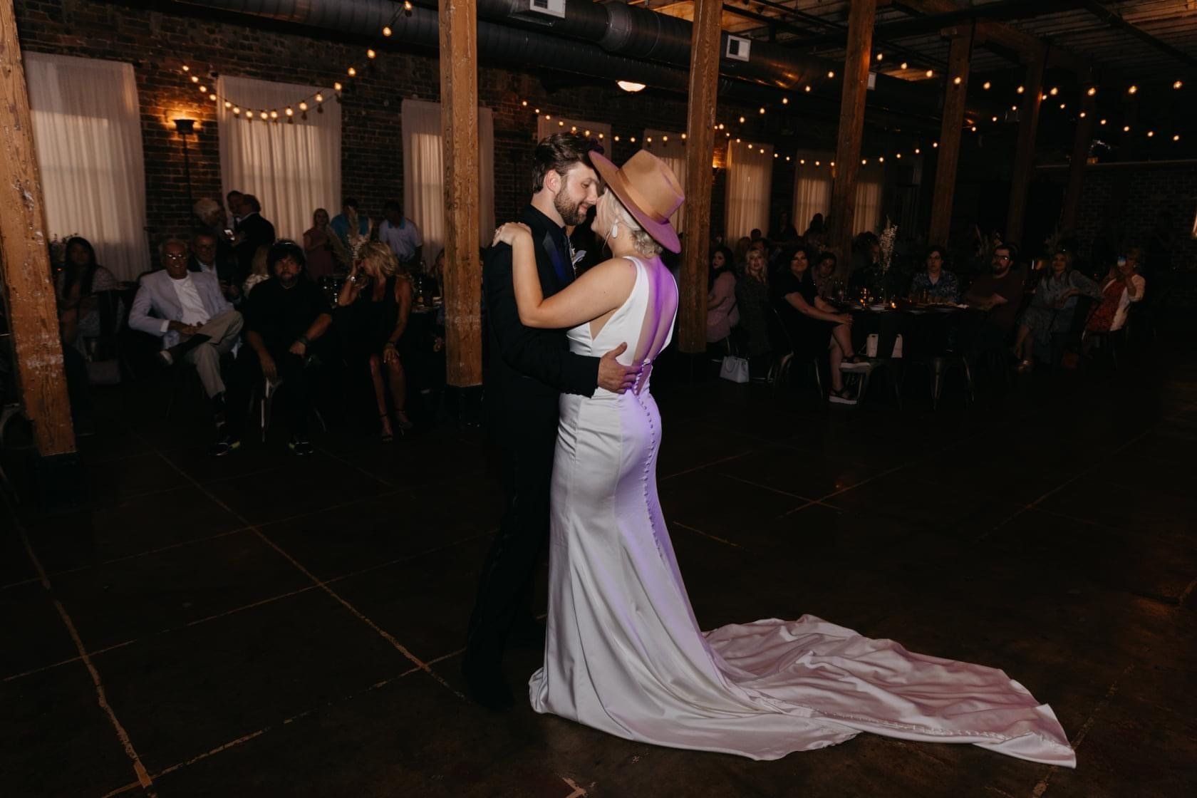 A bride and groom are dancing their first dance at their wedding reception.