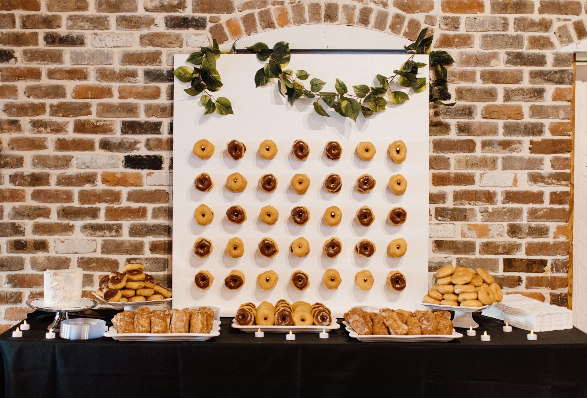 A table with donuts and cookies on it in front of a brick wall.