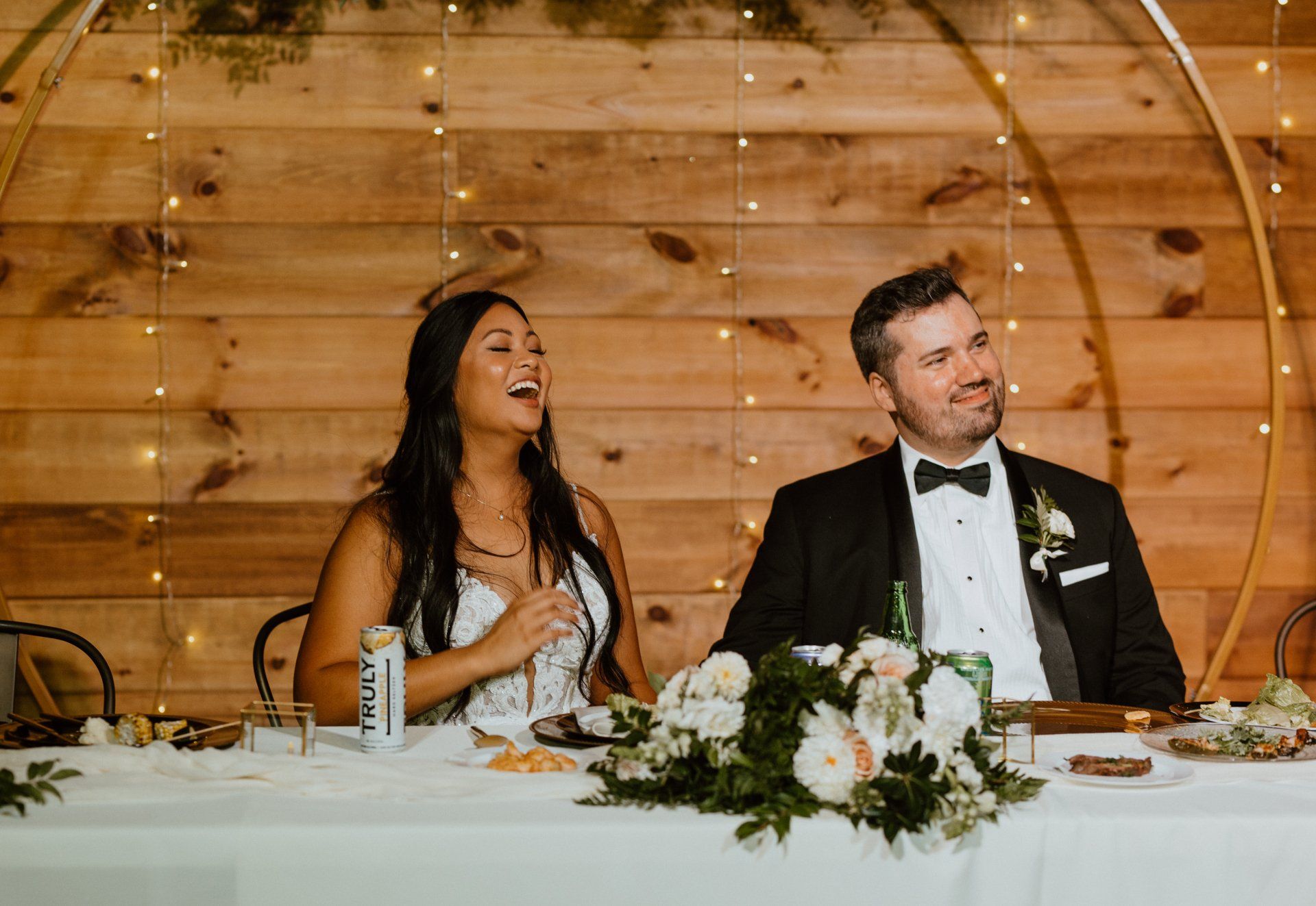 A bride and groom are sitting at a long table at their wedding reception.