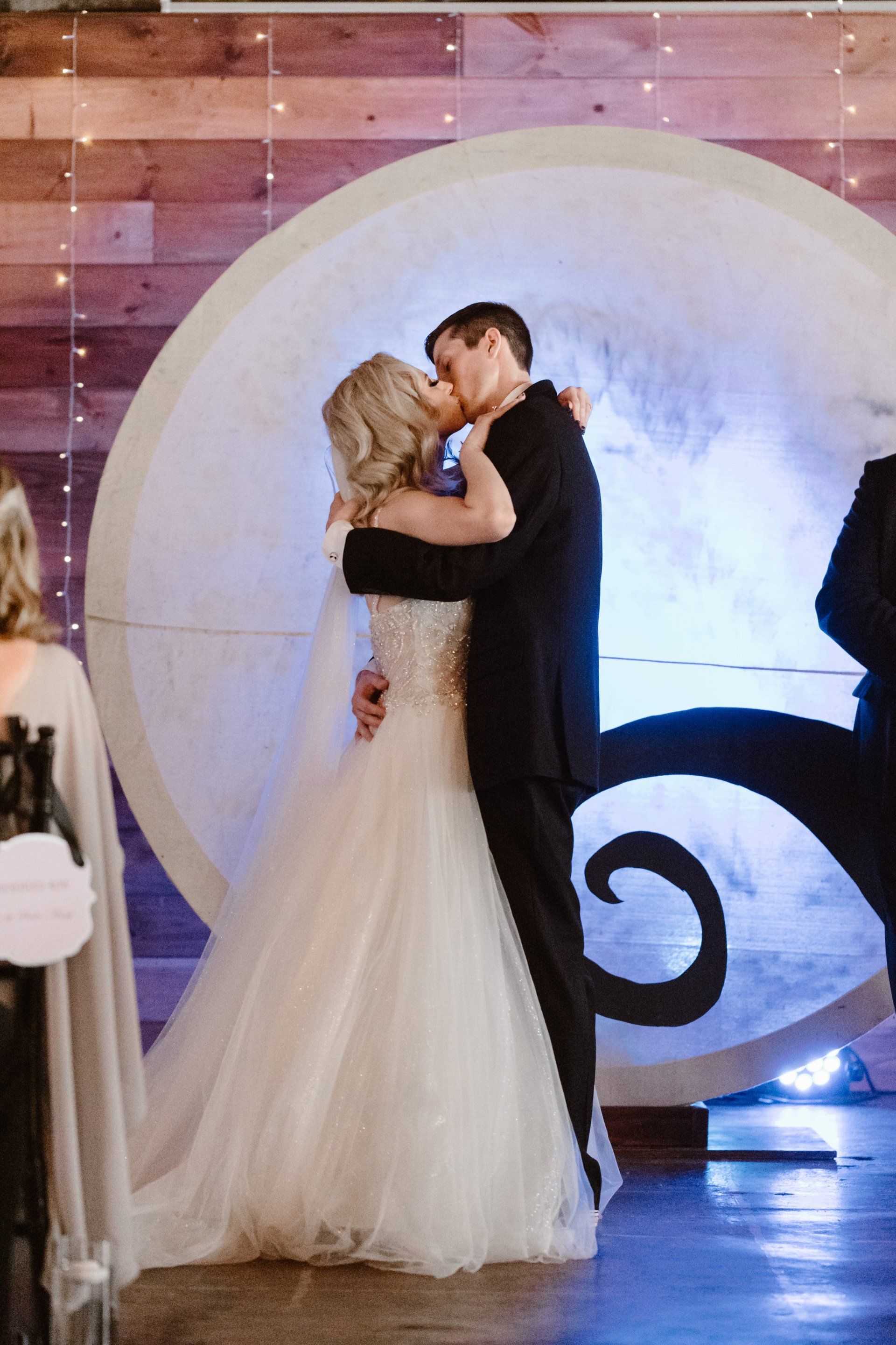 A bride and groom kissing in front of a full moon