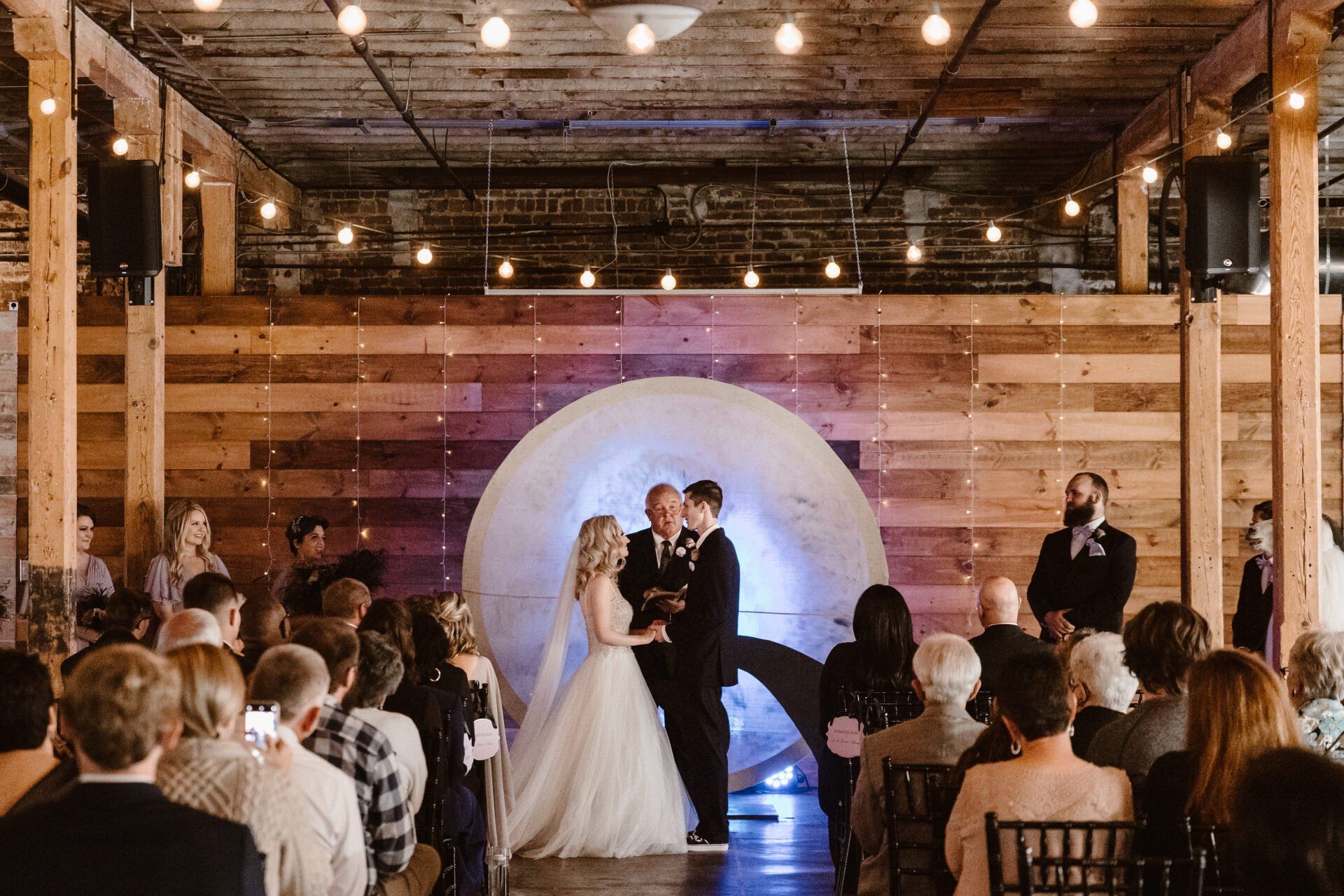 A bride and groom are getting married in front of a crowd at a wedding ceremony.