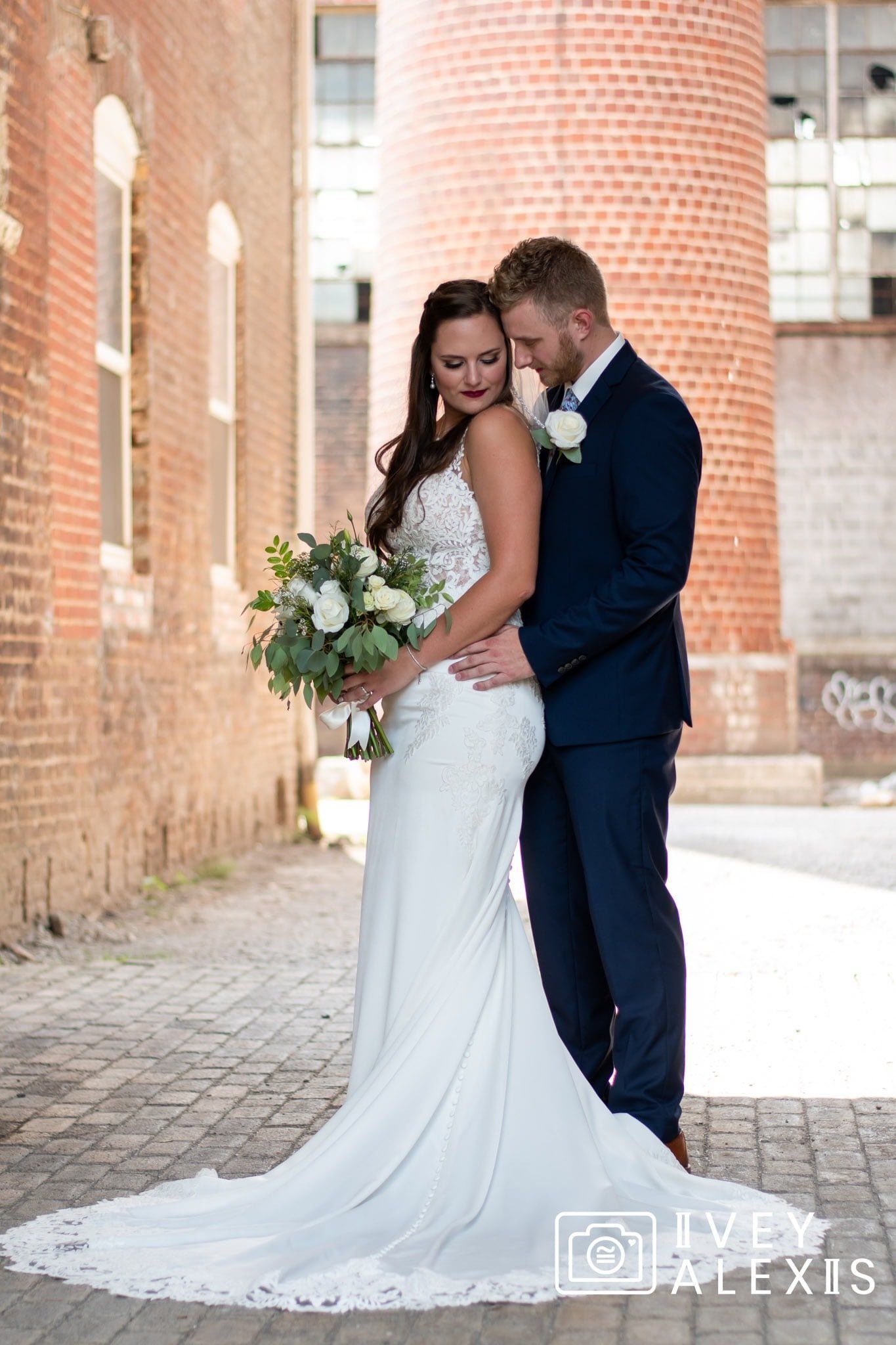 A bride and groom are posing for a picture in front of a brick building.