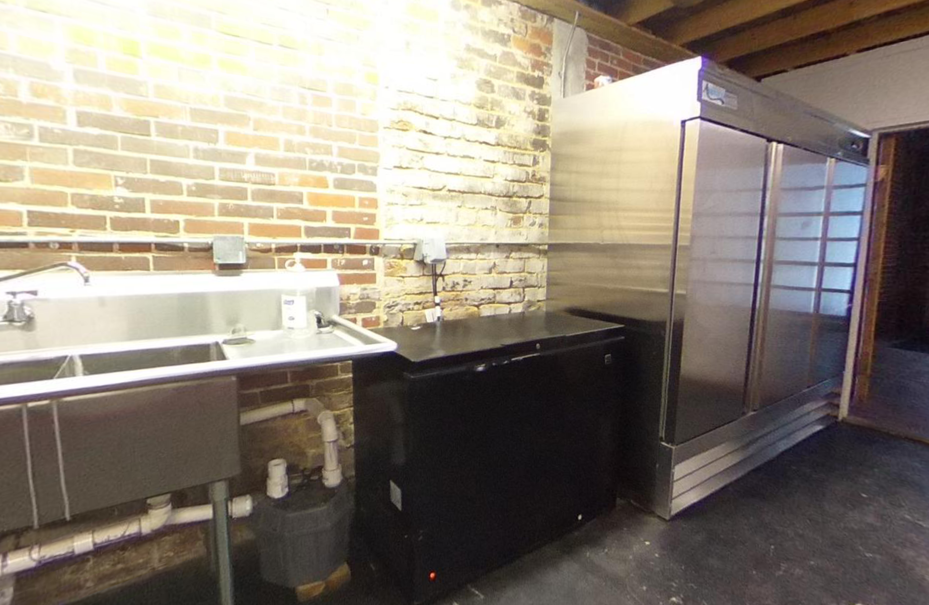 A kitchen with stainless steel appliances and a brick wall