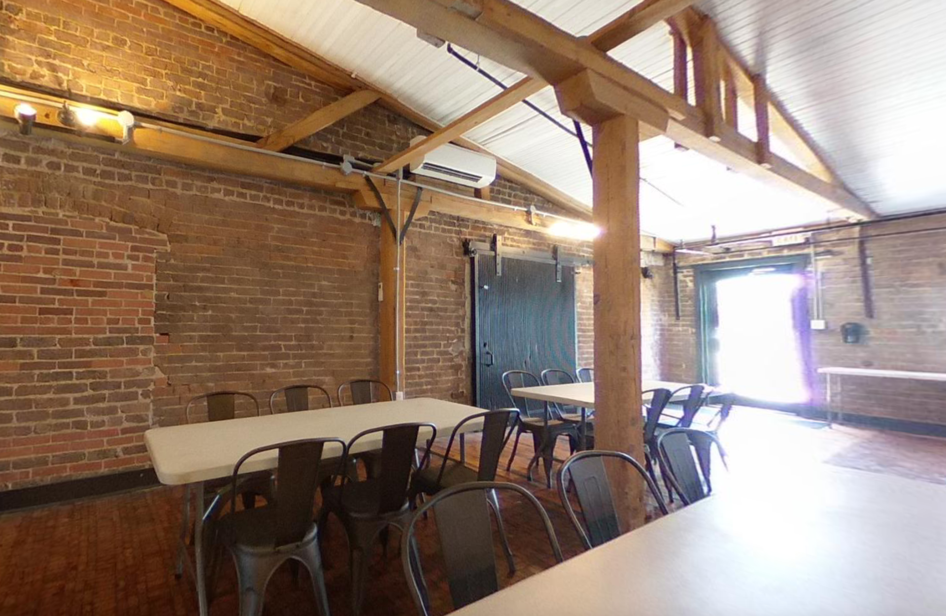 A large room with tables and chairs and a brick wall.