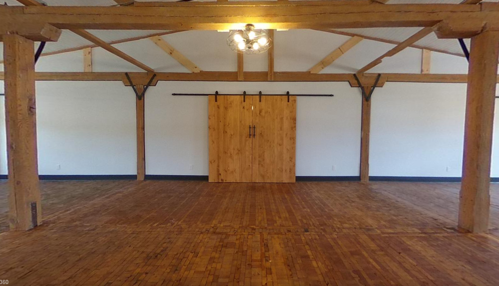 An empty room with a wooden floor and a sliding barn door