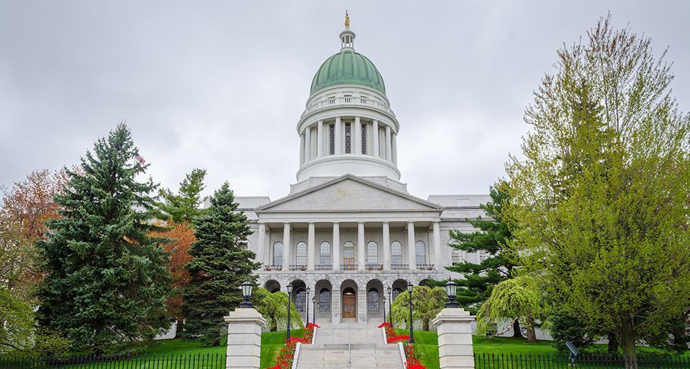 A large white building with a green dome is surrounded by trees – Auburn, ME - Maine Right To Life
