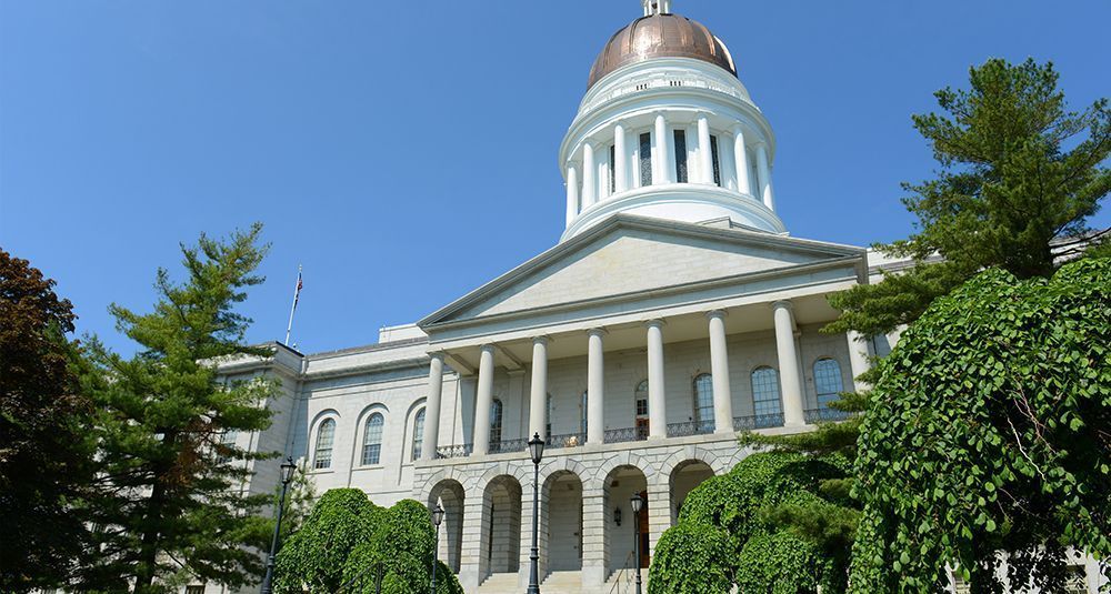 The capitol building is surrounded by trees and a blue sky – Auburn, ME - Maine Right To Life