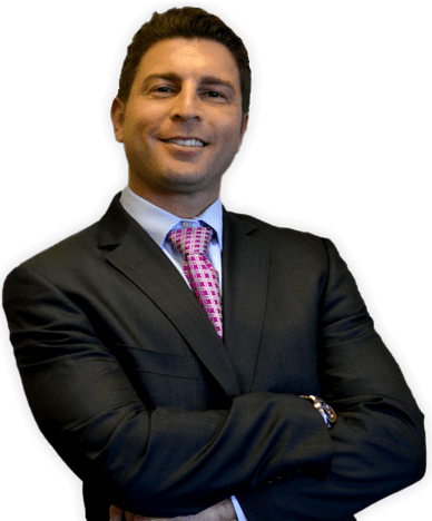 Man in suit with arms crossed, smiling. Pink patterned tie, light blue shirt.