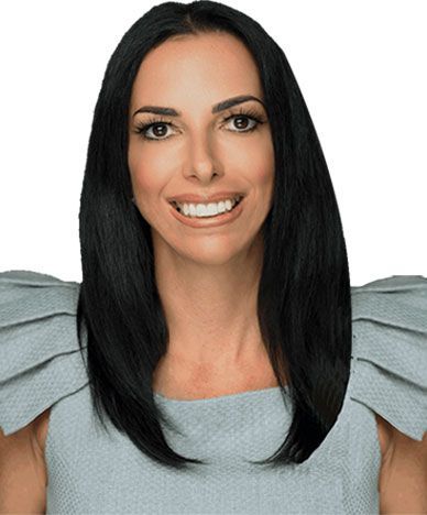 Woman with long black hair, smiling, wearing a light blue dress with textured shoulder details.