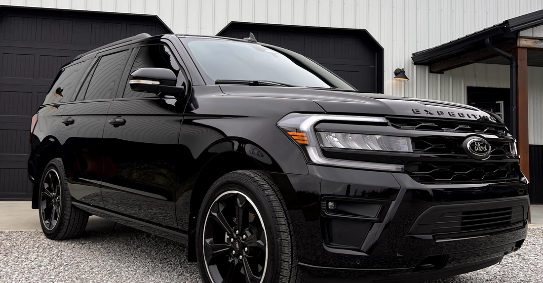 A black ford expedition is parked in front of a garage.