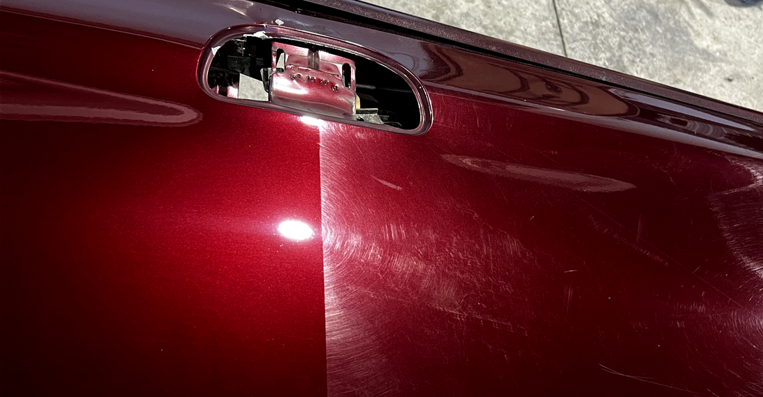 A close up of a red car door with a broken handle.