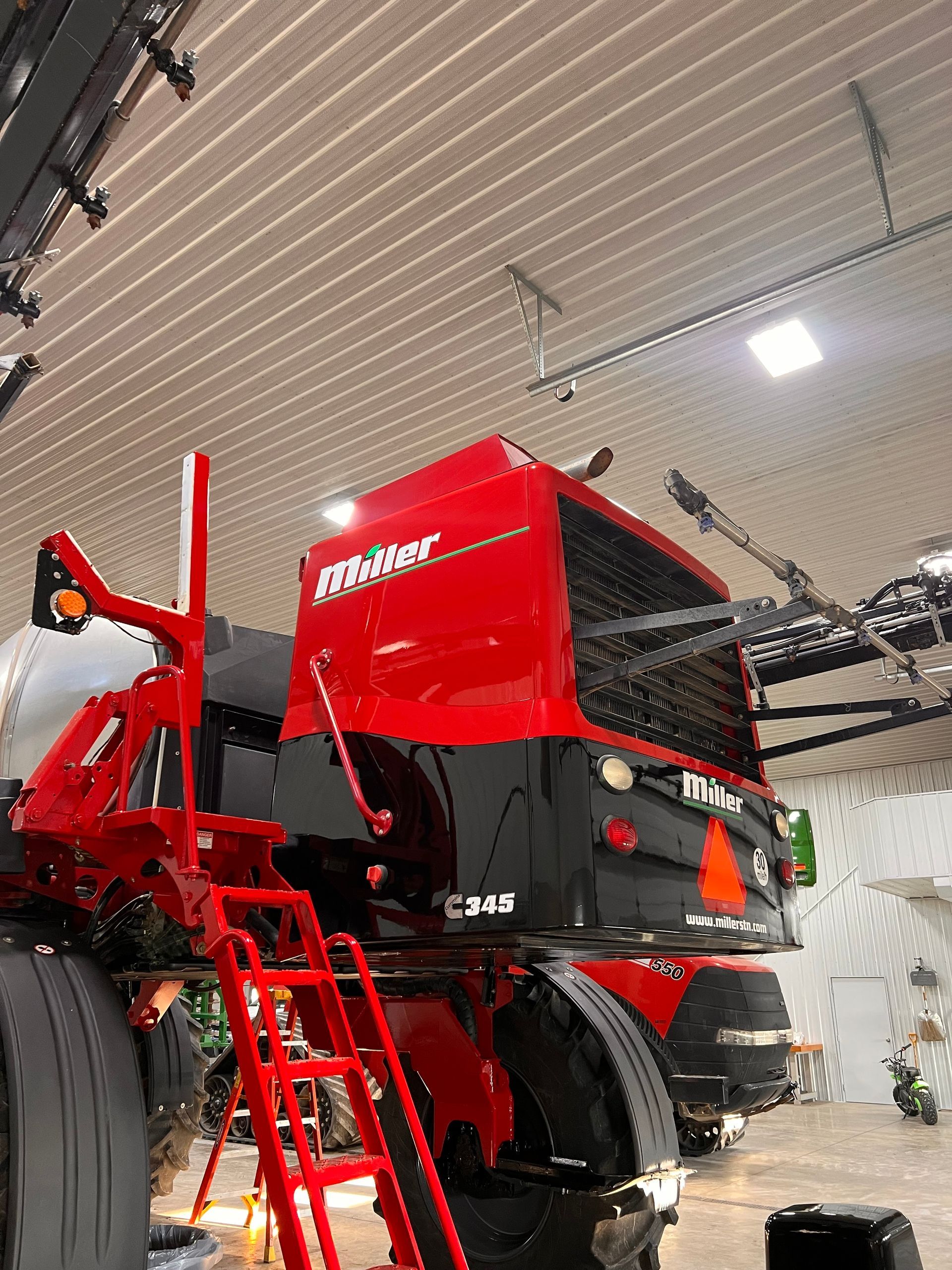 A red and black tractor is parked in a garage.