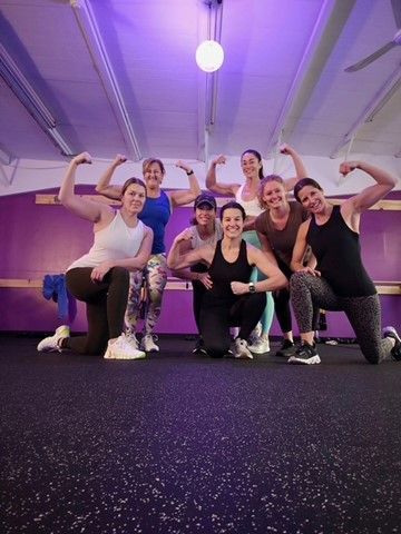 A group of people are posing for a picture in a gym.