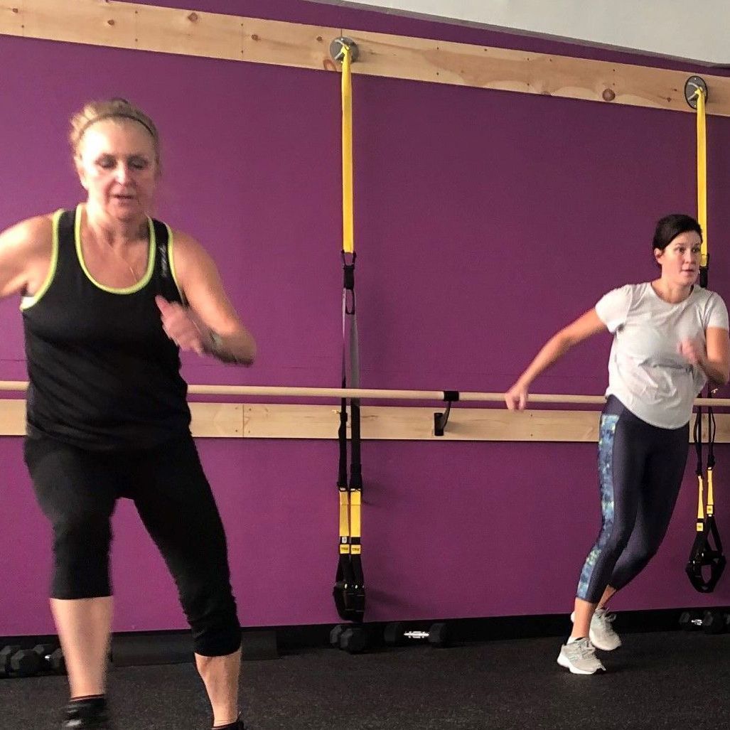 A group of women are posing for a picture in front of a purple wall.